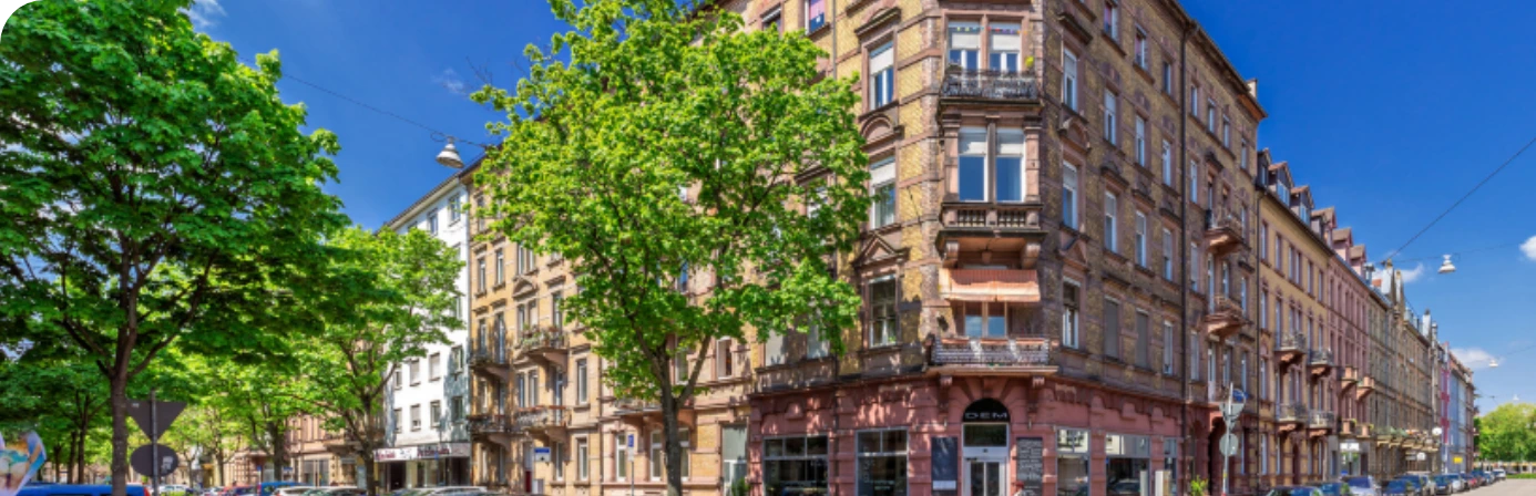 Straßenszene mit historischen Gebäuden und grünen Bäumen in einem lebendigen Stadtviertel von Karlsruhe.
